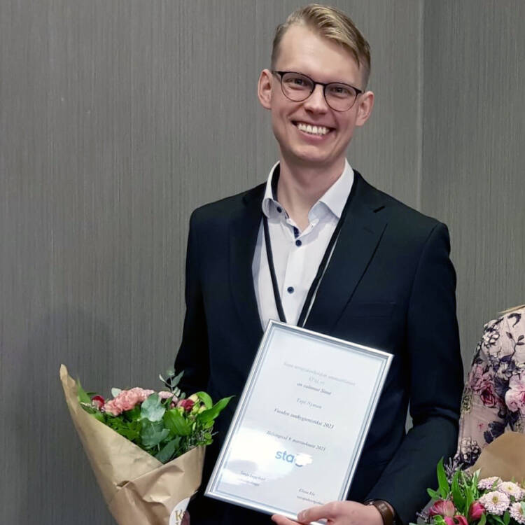 Vuoden 2023 suuhygienisti Topi Nyman hymyilee iloisesti tunnustuksen saamisen jälkeen kukkien ja diplomin kera.