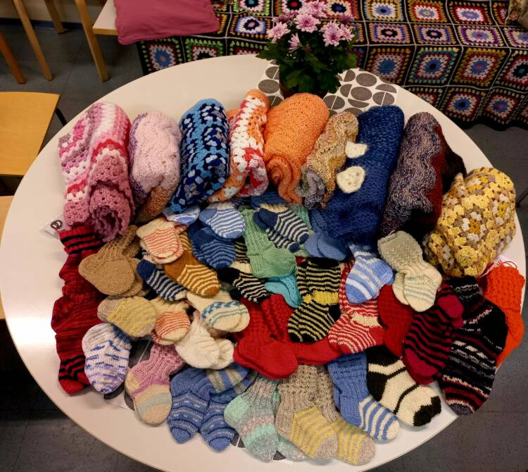 Valokuvassa värikkäitä sukkia ja muita vauvaperheille neulottuja lahjoitustuotteita.